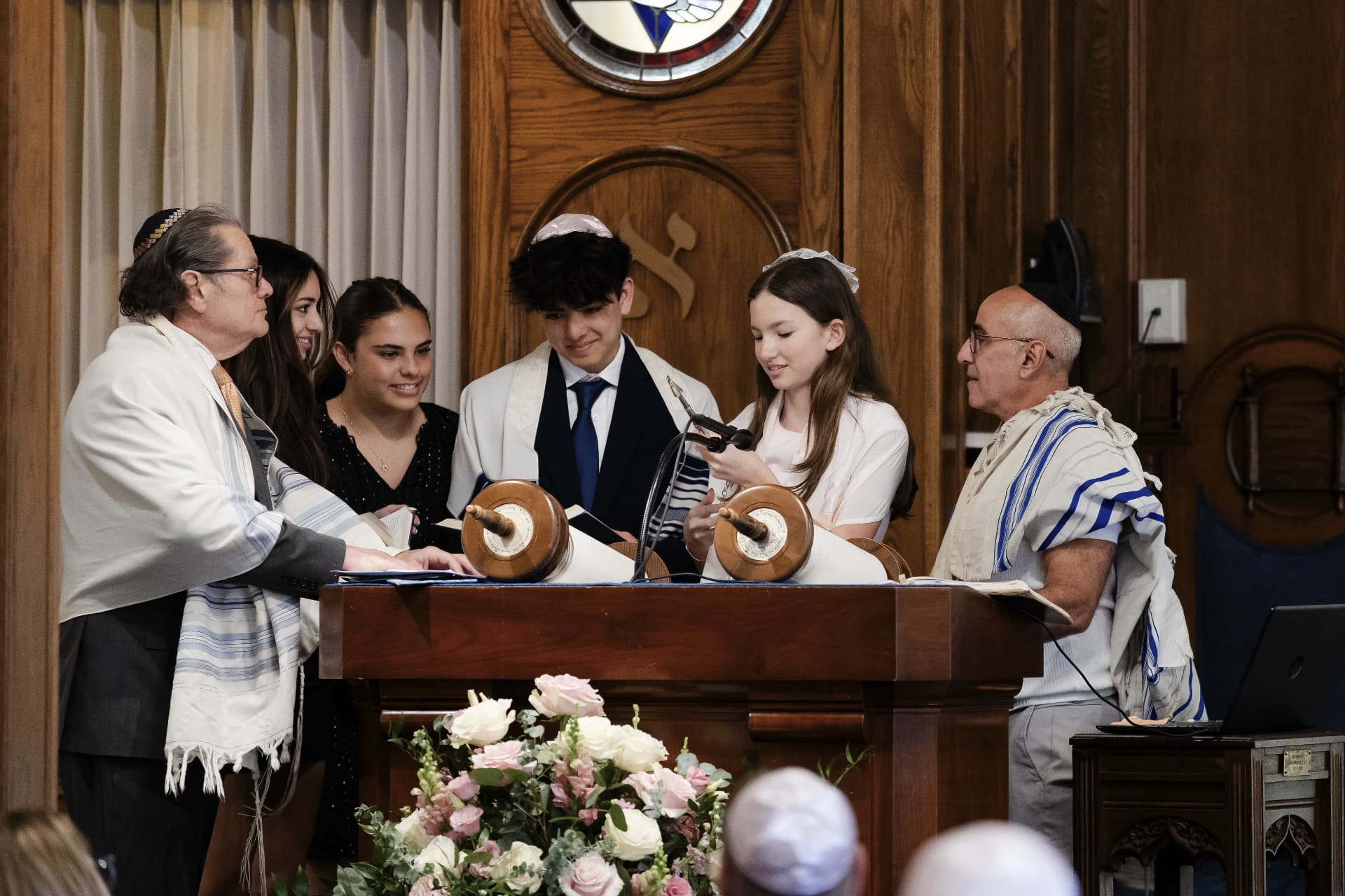 Teens and clergy gathered around the Torah on the bimah at a b'nai mitzvah