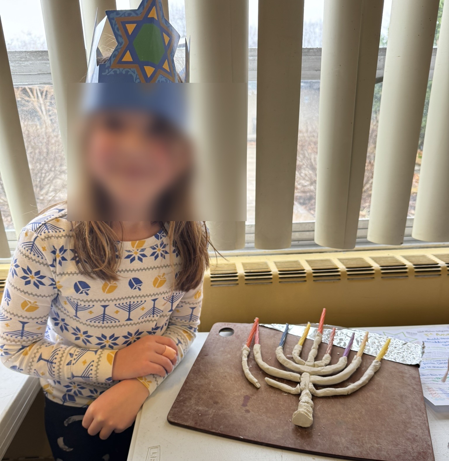 Preschool child with a handmade clay menorah craft